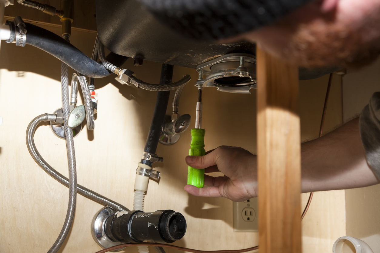 Man tightening screws around garbage disposal flange