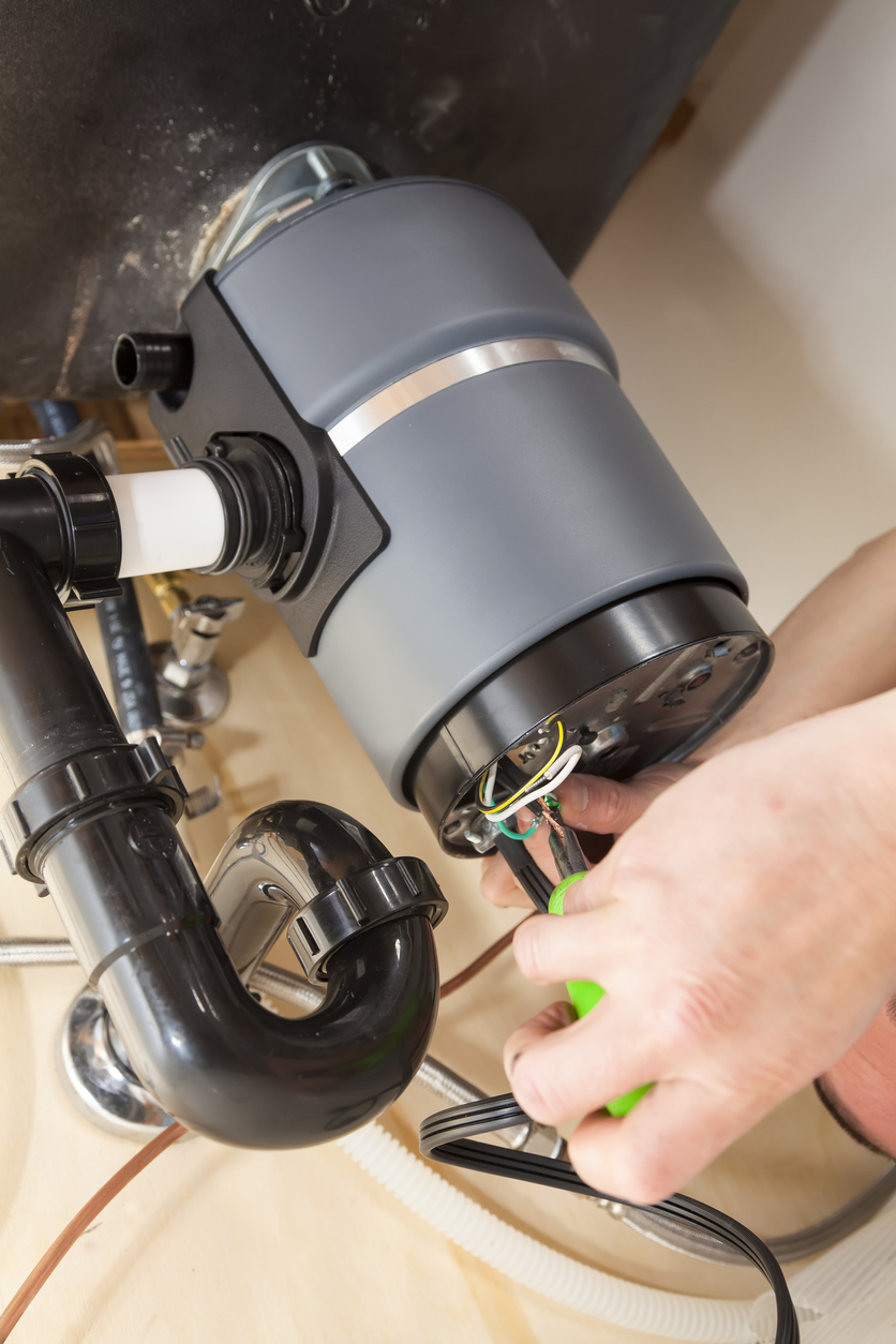 Man wiring new garbage disposal under sink.