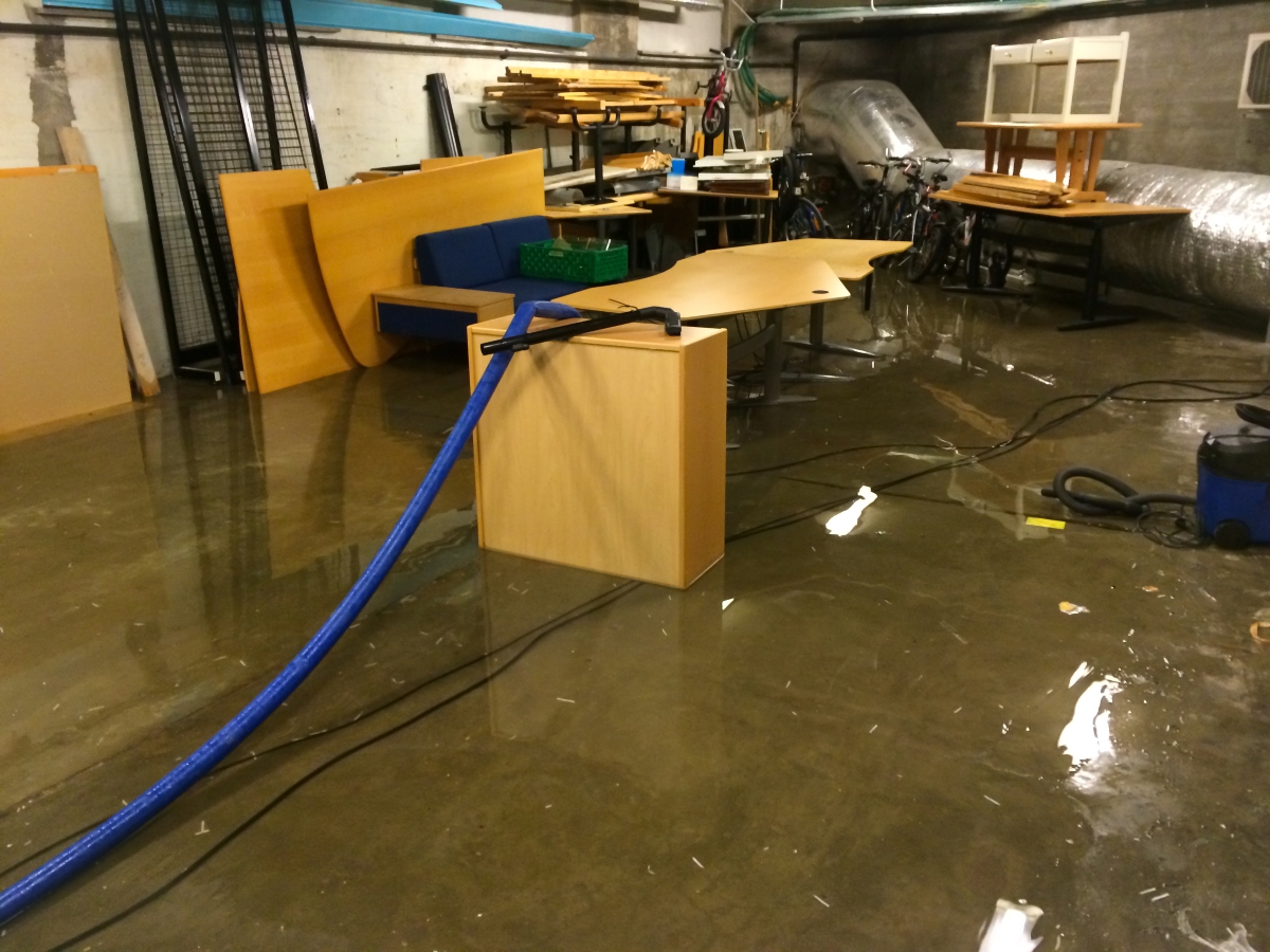 A basement filled with furniture and bikes flooded with water