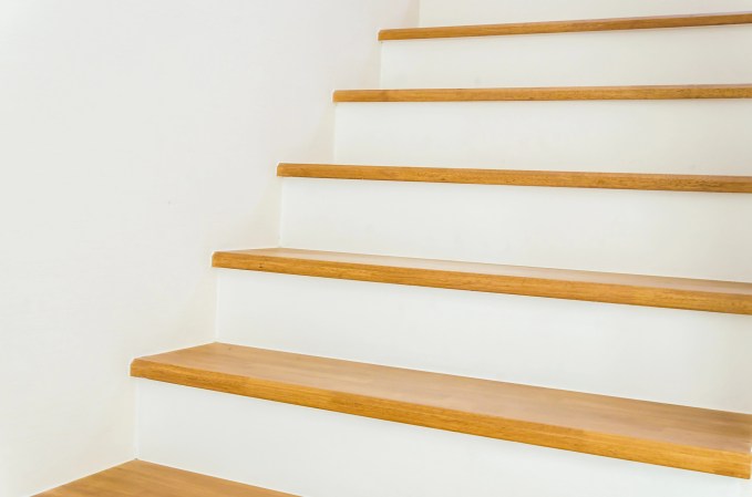Stairs with white risers and light wood treads with a white wall in the background.