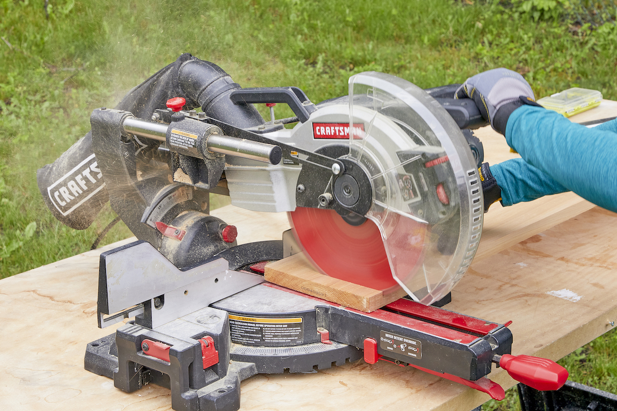 Woman uses a miter saw to square a piece of wood.