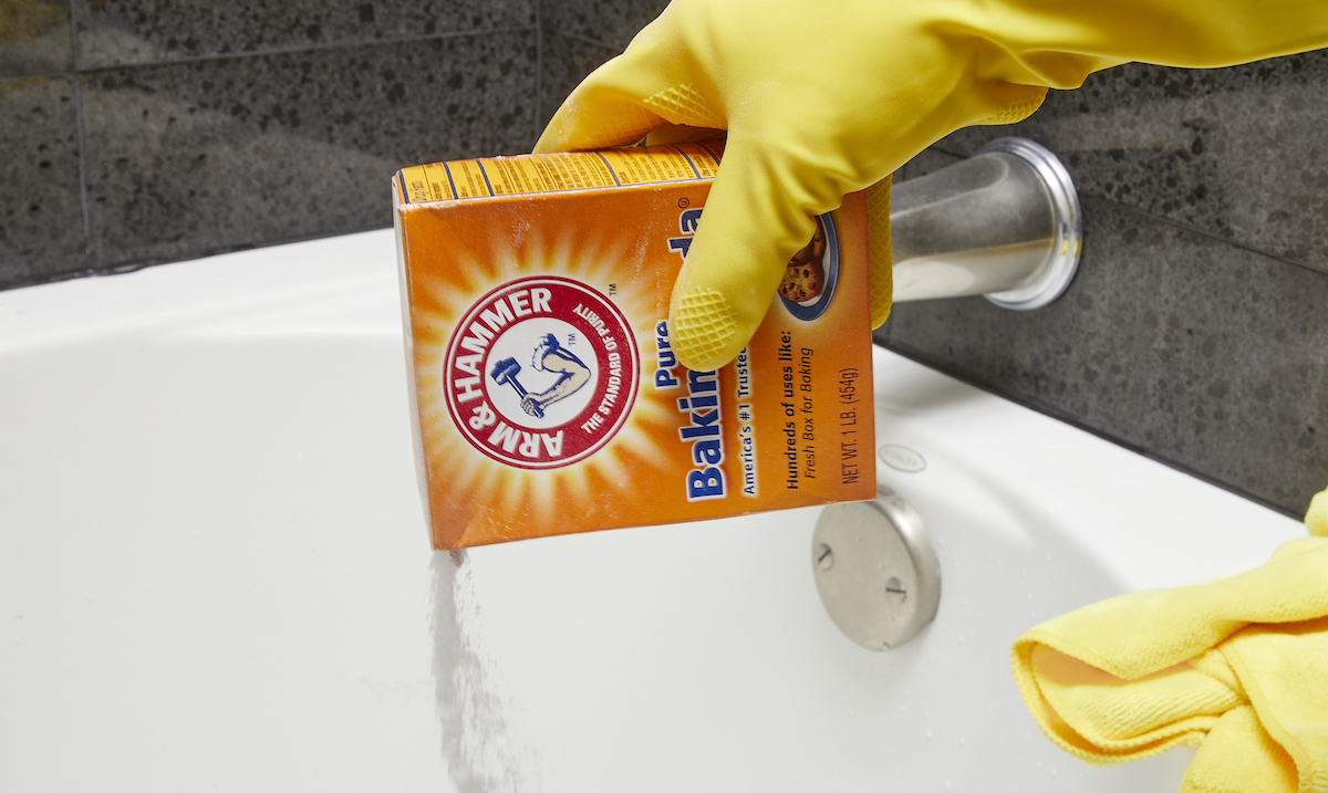 Woman pours baking soda into a bathtub.