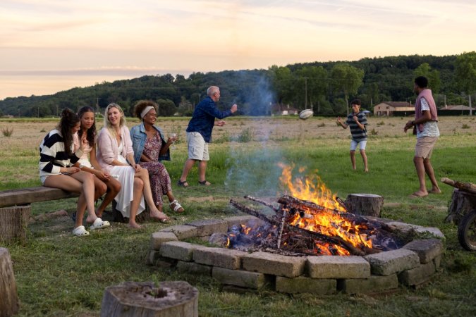 A family sitting around the fire and enjoying activities.