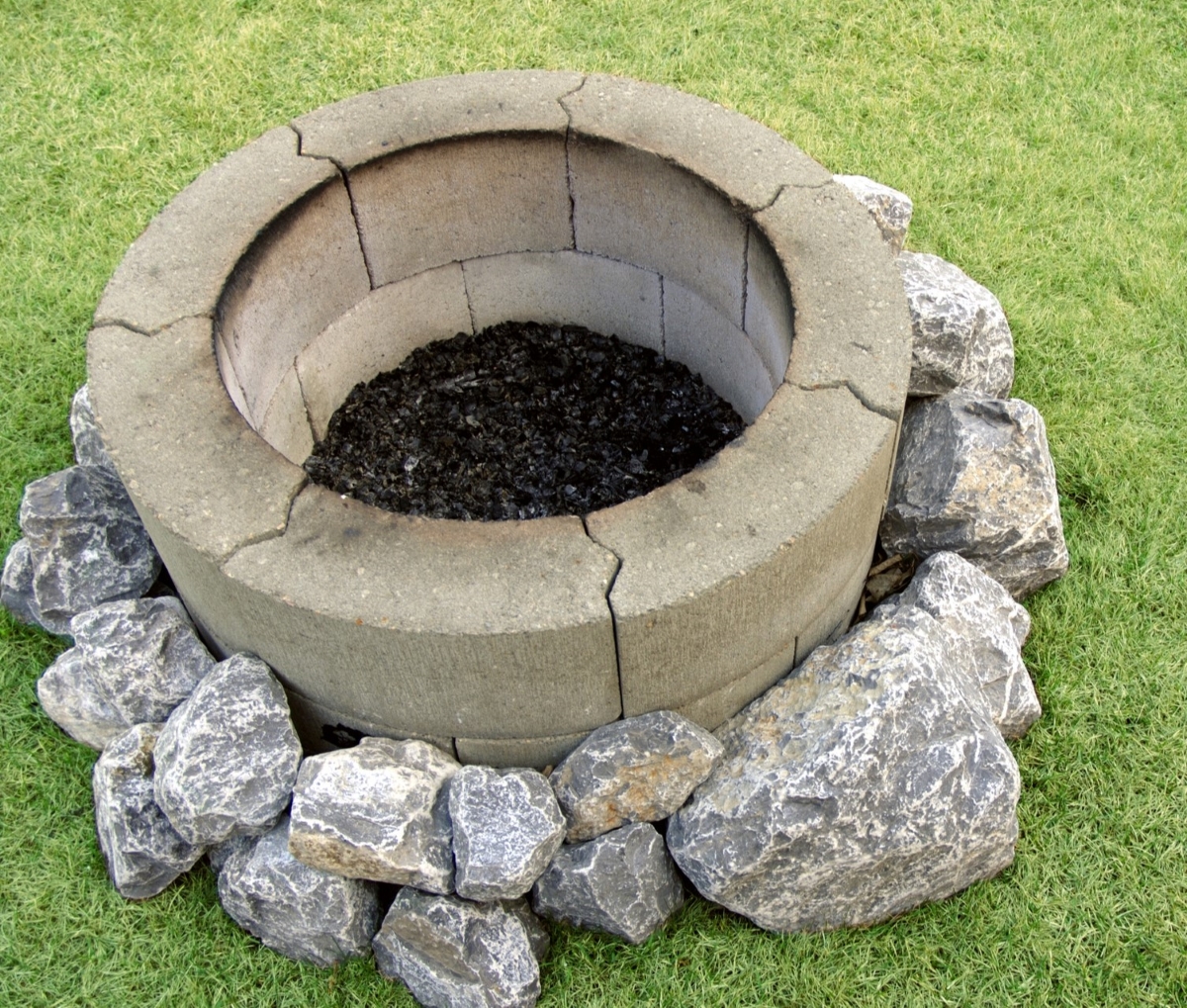 A fire pit built with fire bricks and surrounded by large rocks.