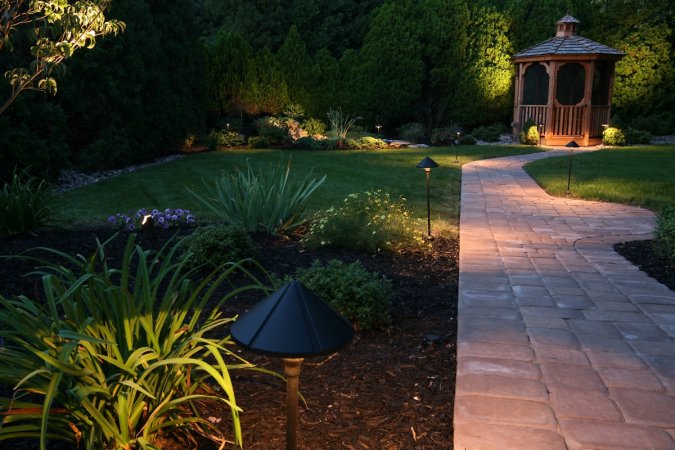 A backyard at night, illuminated with outdoor path lights