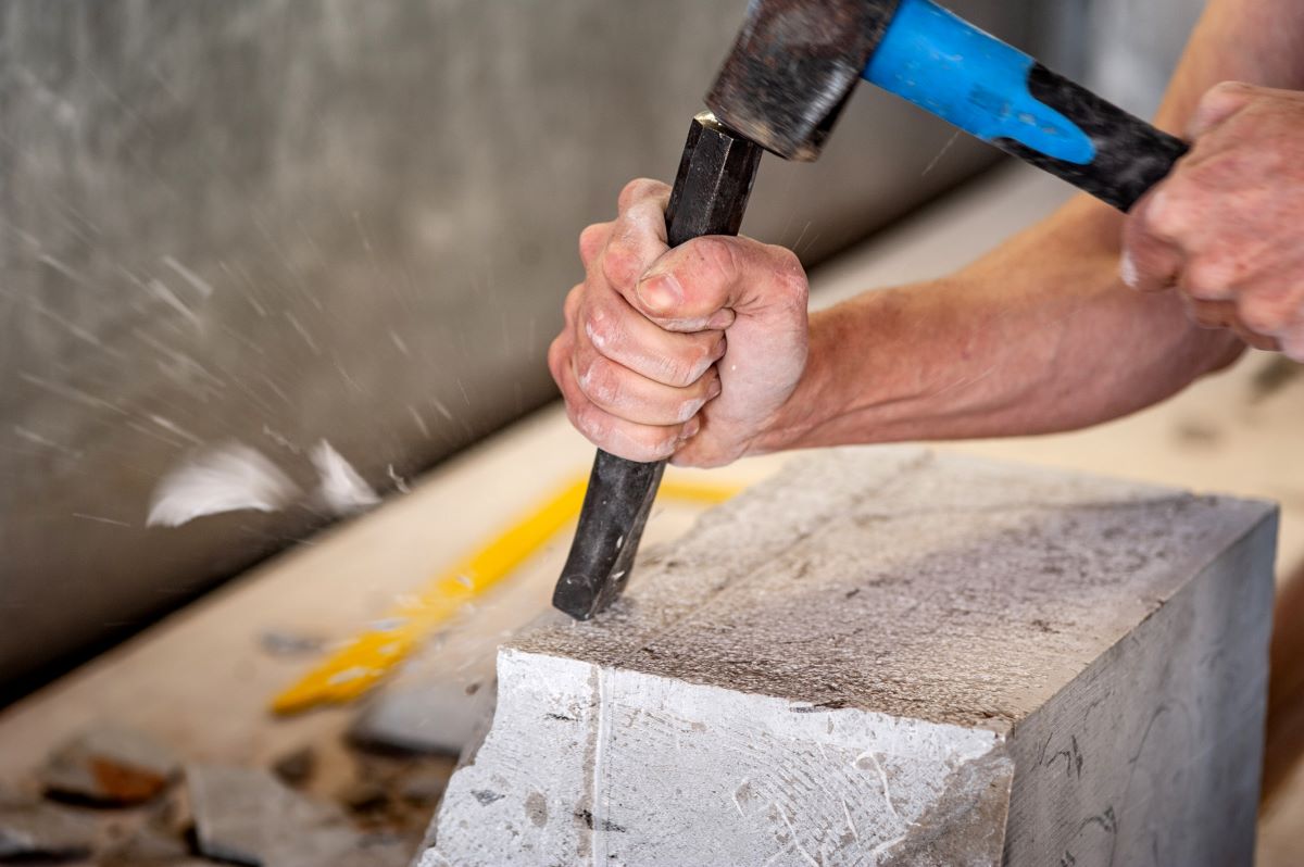 Man using a hammer and chisel on a piece of stone