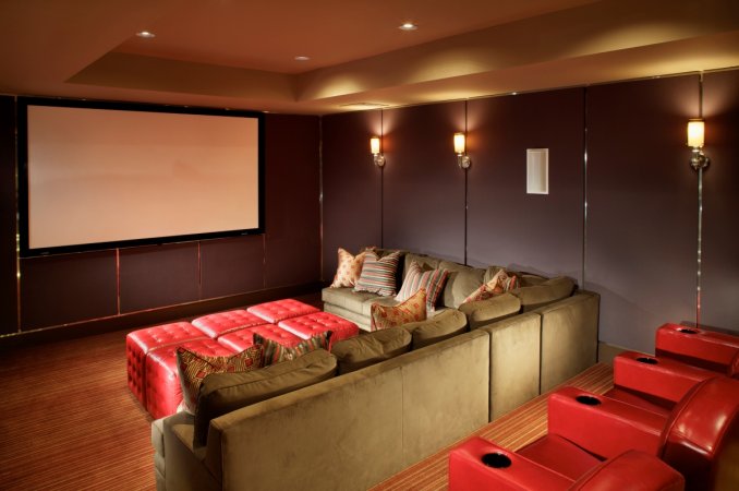 A home theater with a large L-shaped sofa and red recliners