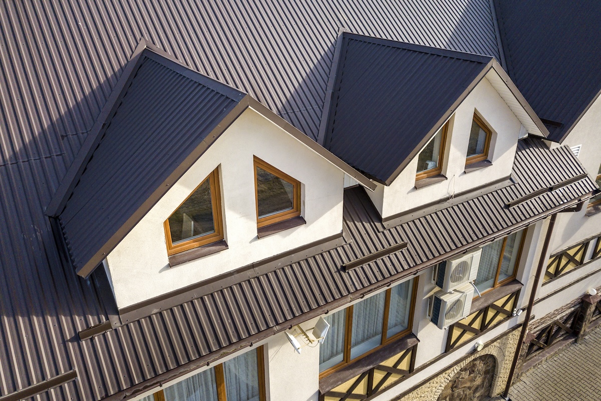 A large white home with wooden window panes and a grey metal roof.