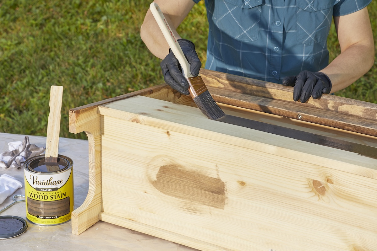 Staining a wooden shelf on an outdoor work station.