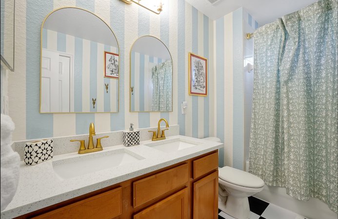 Orange peel textured blue-and-white striped walls in an Alice in Wonderland-themed bathroom.