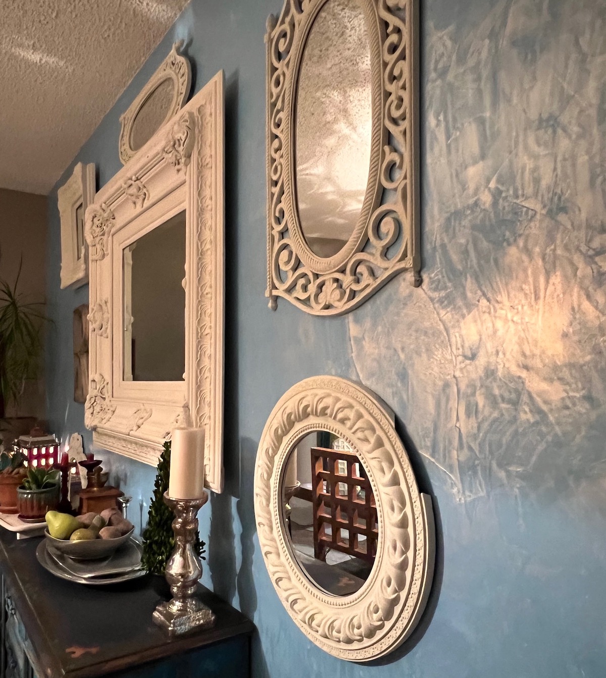 Room with popcorn ceiling, mirrors on a light blue painted wall, with Venetian texture and gold wax on top.