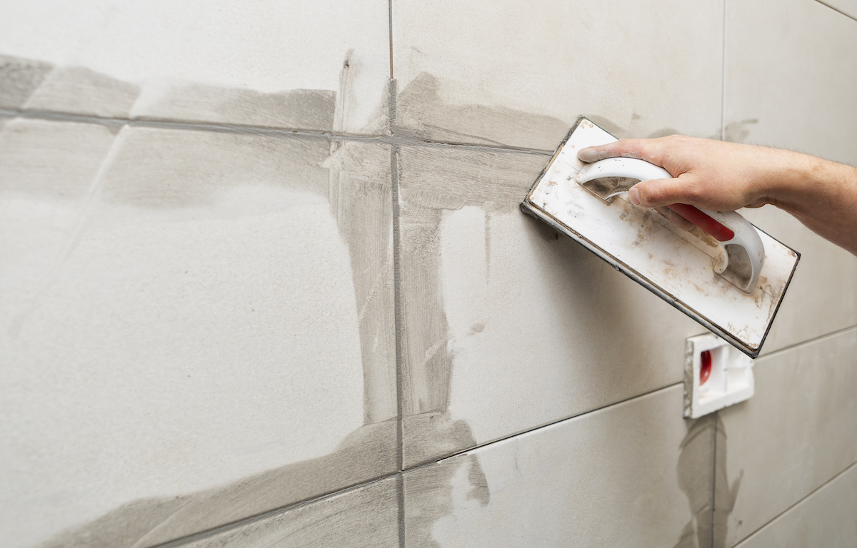 Grouting ceramic tiles. Tilers filling the space between tiles using a rubber trowel.