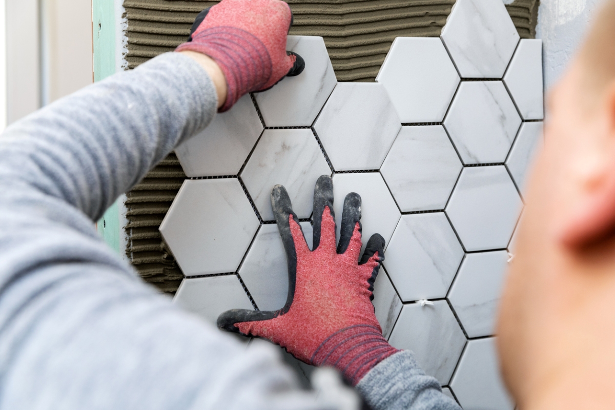 how to tile a bathroom wall - person using tile on wall