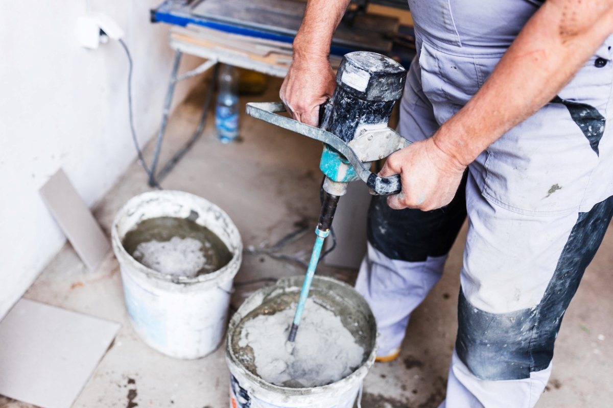 how to tile a bathroom wall - person using machine to mix materials