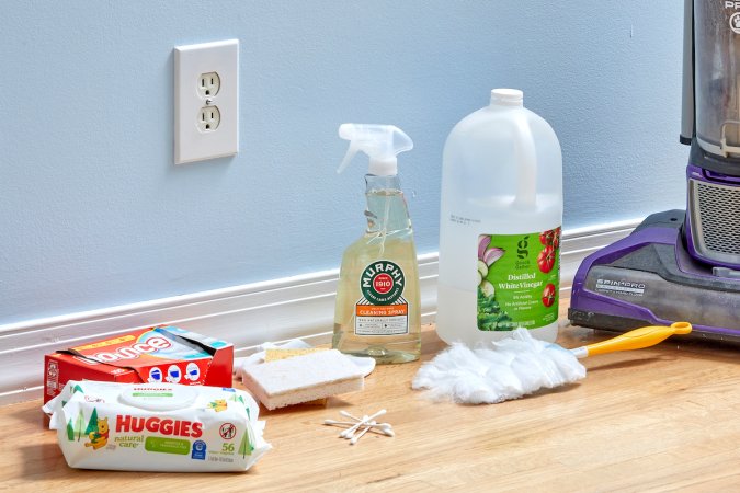 Materials needed to clean baseboards, including dryer sheets and baby wipes, assembled on a hardwood floor.