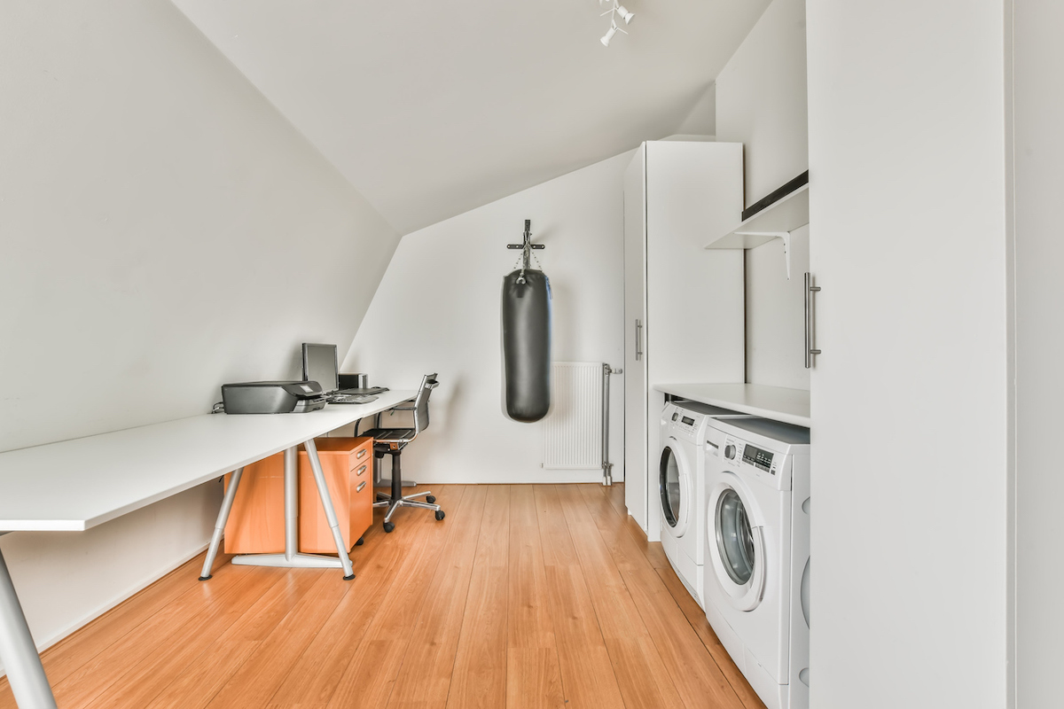 A minimalist home office with a laptop and printer also features a washing machine and dryer.