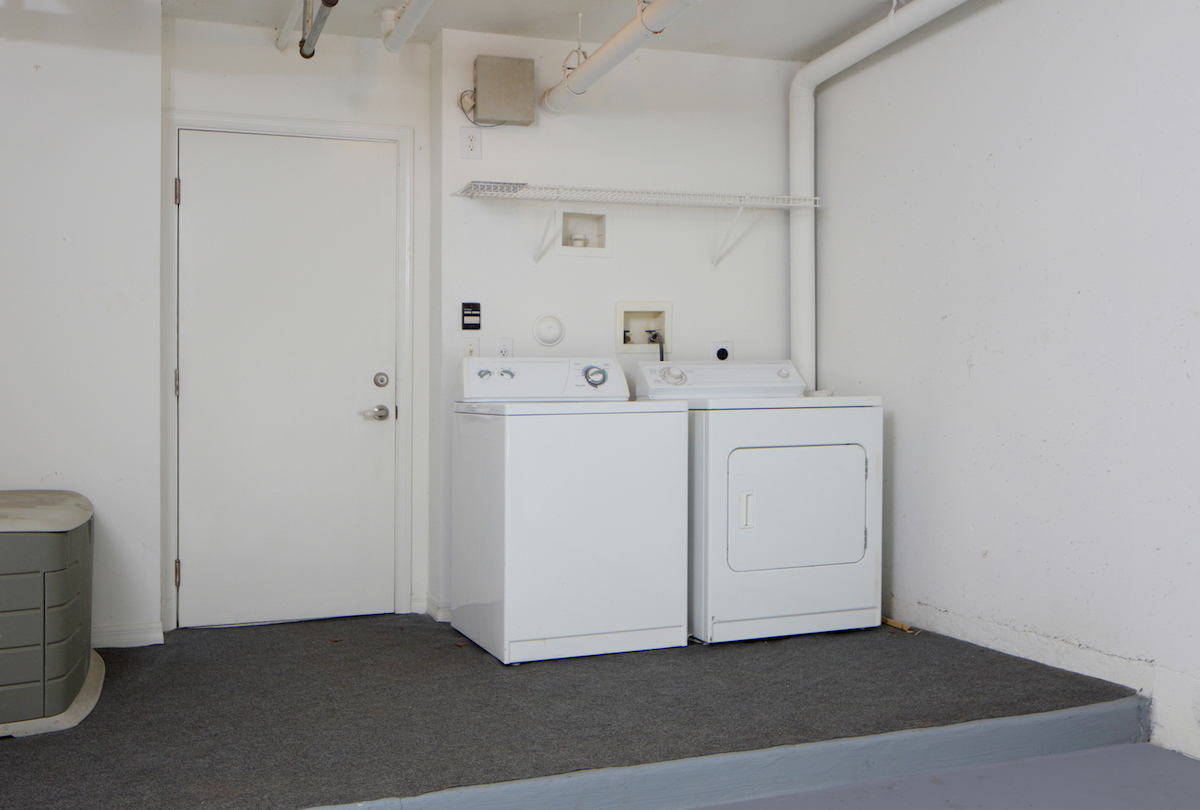 A washing machine and dryer are inside of an otherwise empty garage.