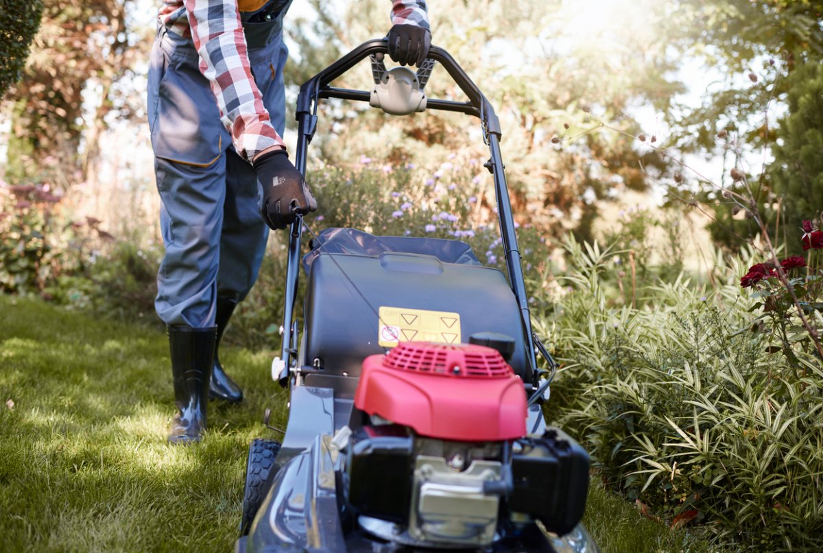 gardener starting lawn mower in garden