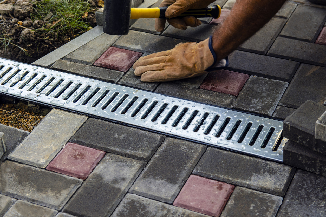 Installation of iron drainage system and paving slabs. a close-up of an iron grating along the sidewalk. Selective focus.