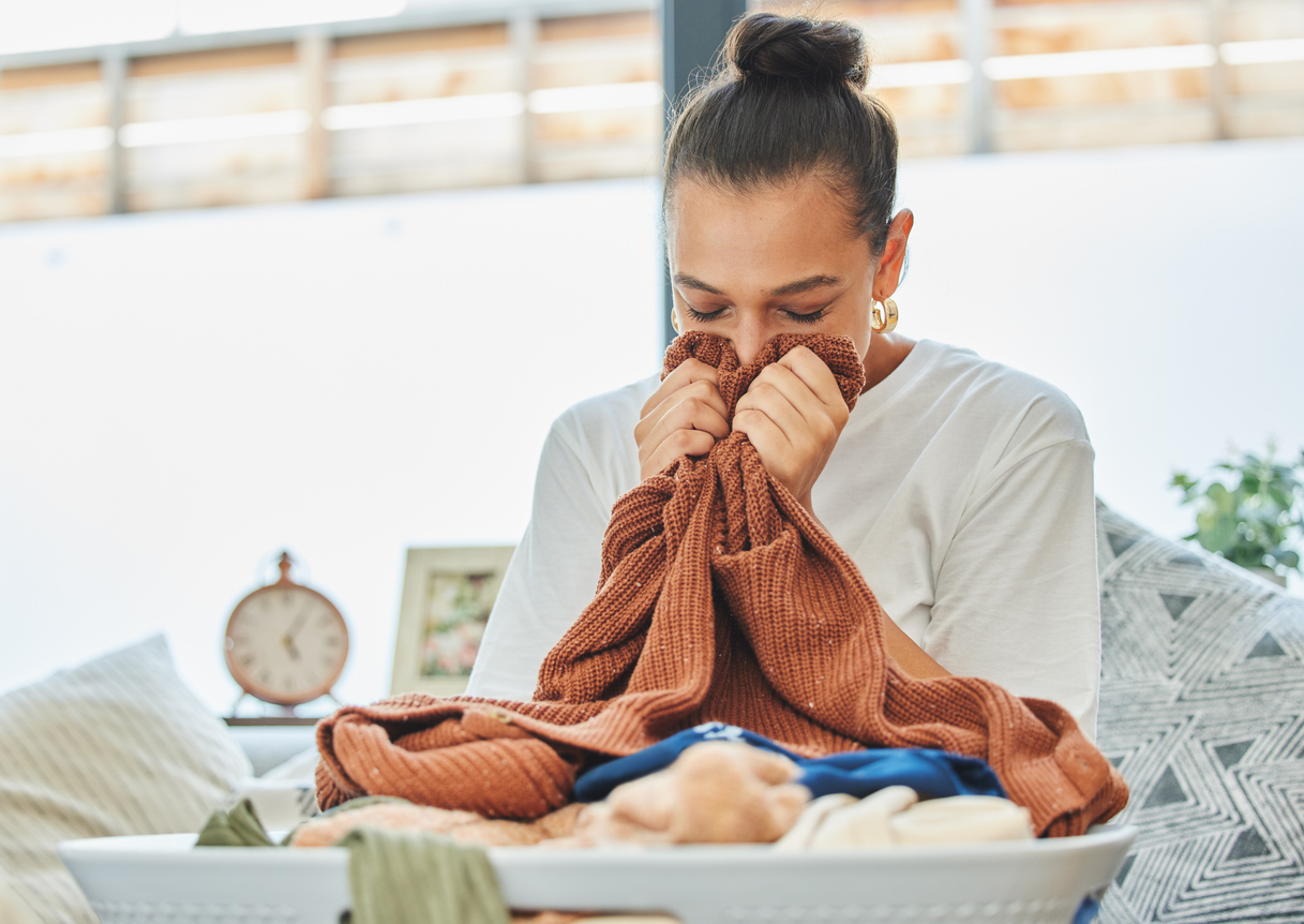 Shot of a young woman sniffing a clean load of laundry