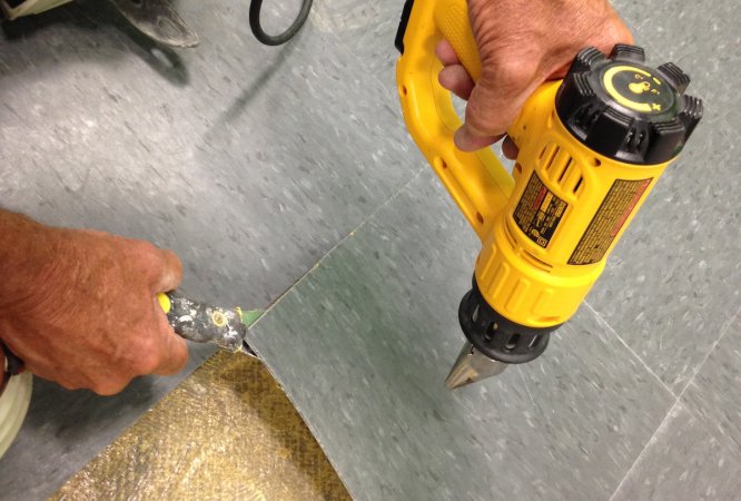 Removing old glued down vinyls tile flooring by applying heat.