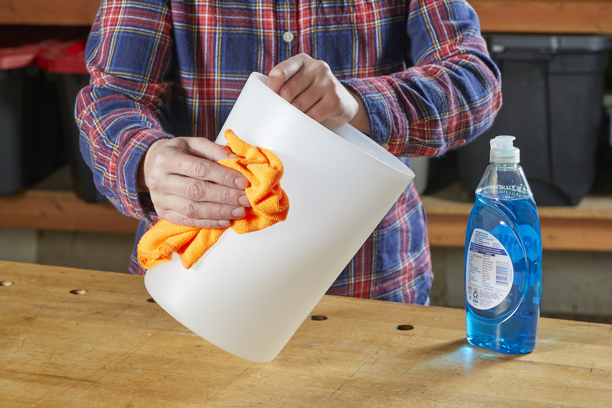 Person using cloth to clean plastic bin.