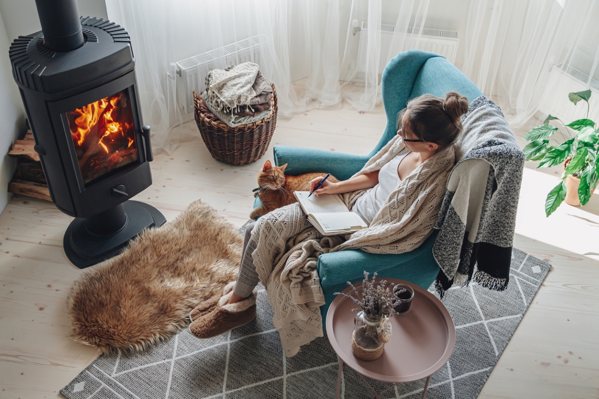 wood stove heat - woman enjoying wood stove fire