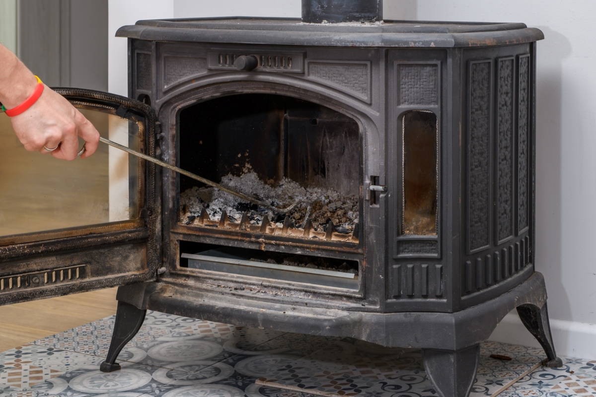 Person removing ashes from wood stove.