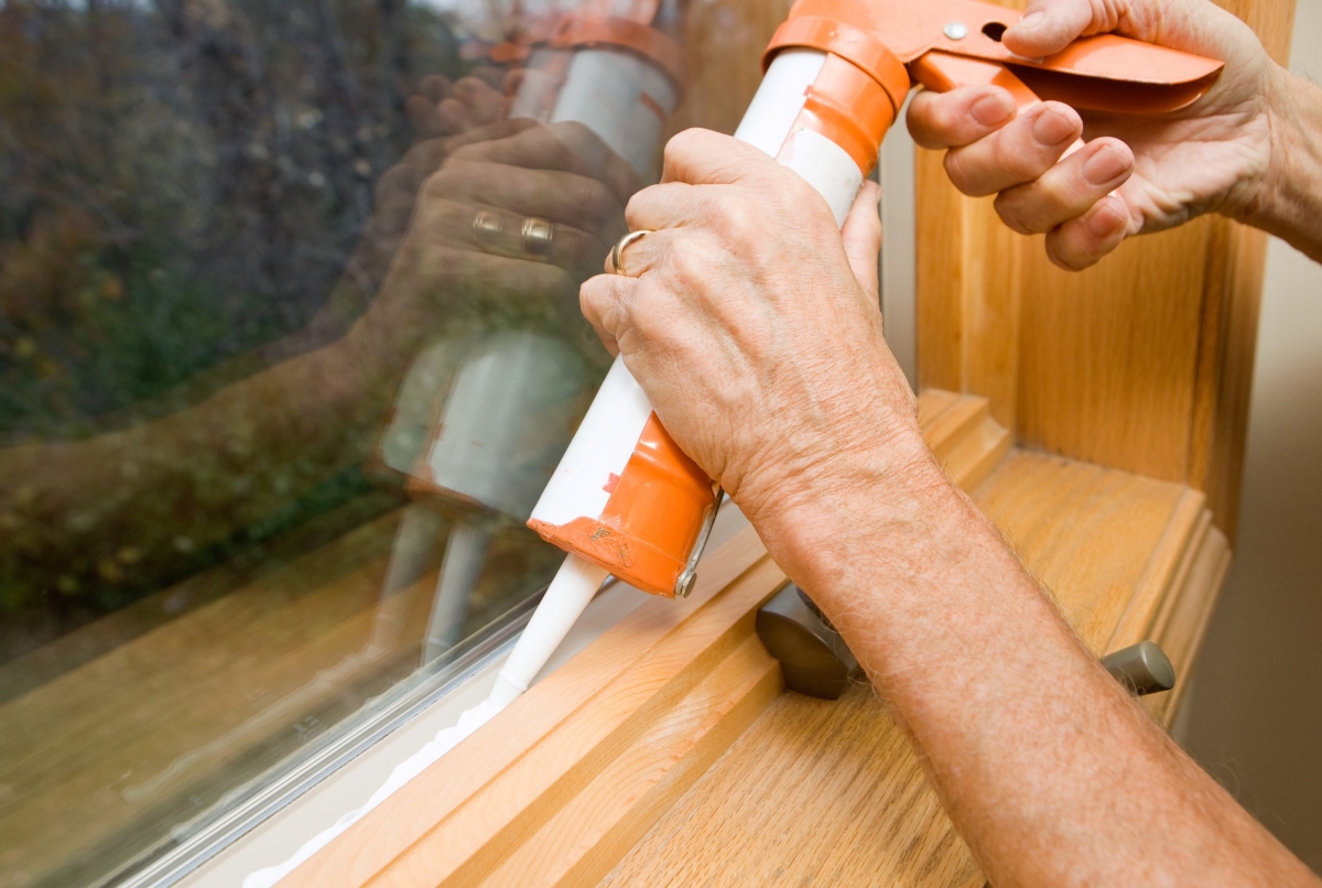 Person is caulking along the window sill.