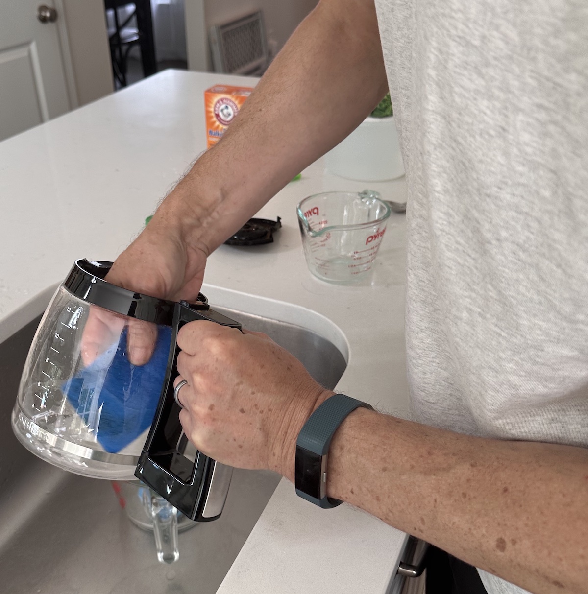 Man washing coffee maker carafe with sponge