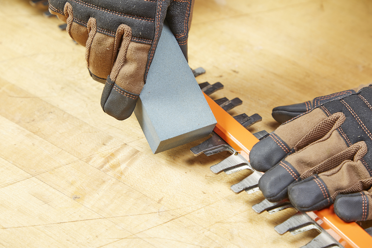 Removing burrs from hedge trimmers with whetstone.