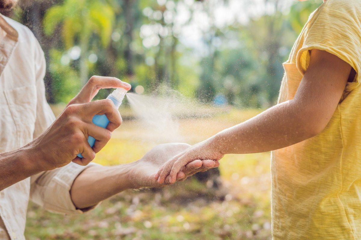 dad and son use mosquito spray.Spraying insect repellent on skin outdoor.