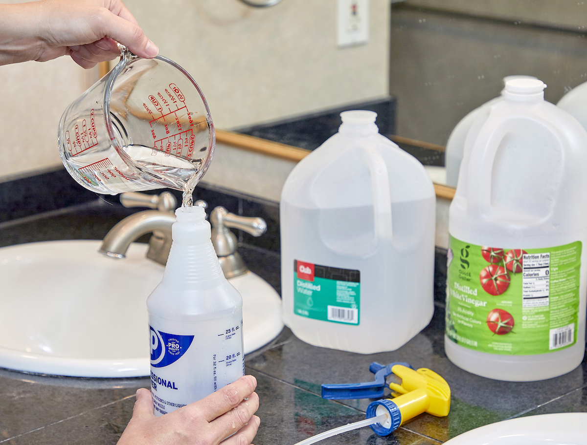 Woman makes a homemade glass-cleaning solution that contains vinegar and other ingredients.