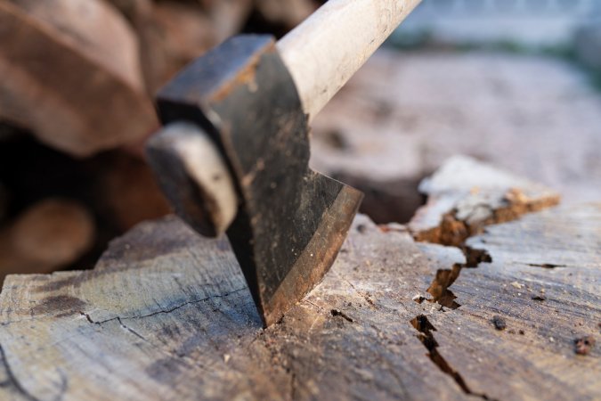 Close up of an ax with its blade pointed into the round of a log.