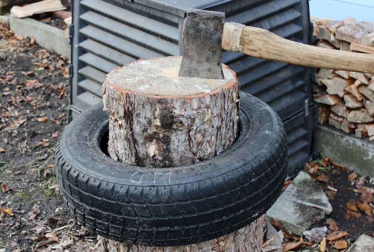 An ax in a log in an old tire to help keep chopped wood in place.