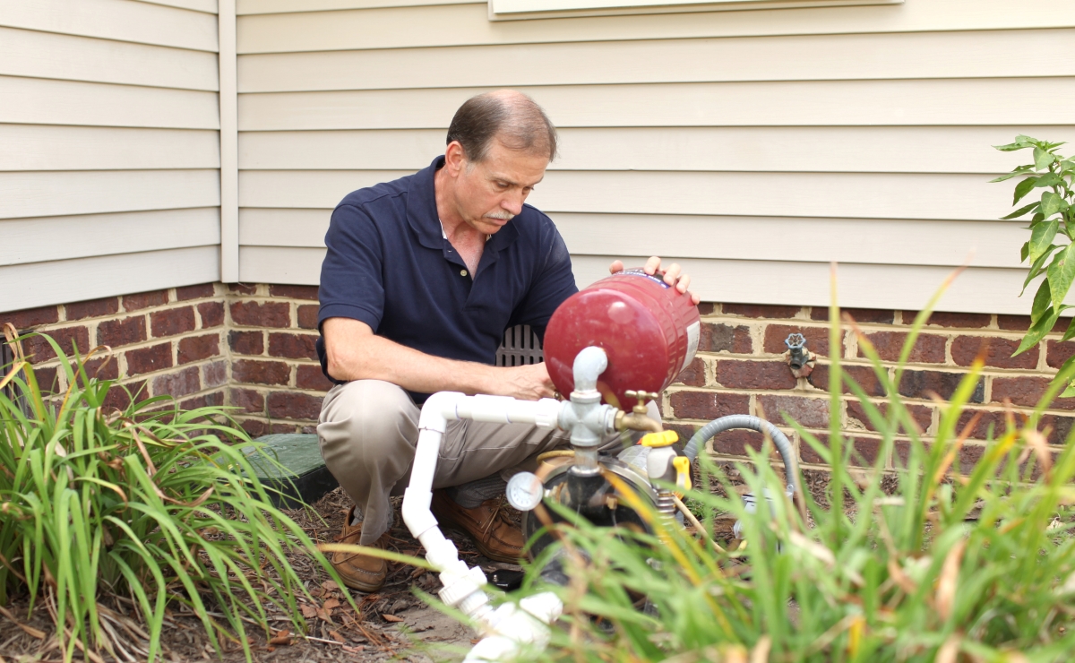 A man is checking the home's well pump outside his house.