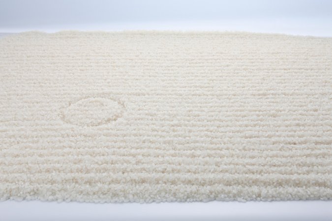 A cream-colored carpet with indentation from furniture.