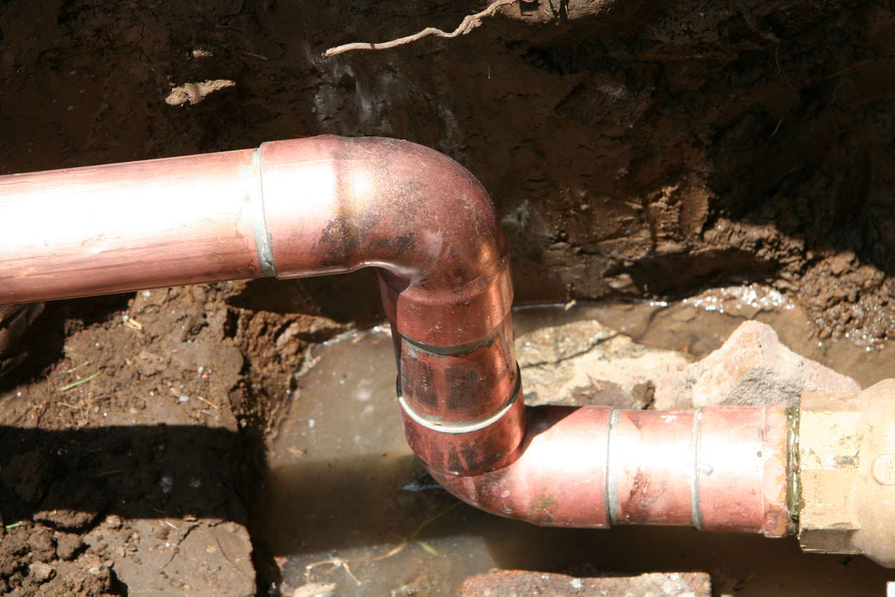 A copper water pipe leaks in a basement.