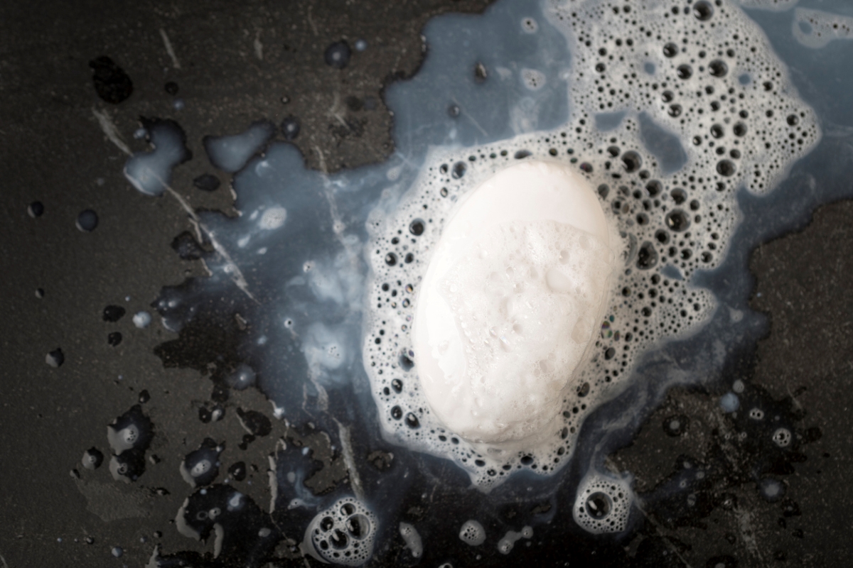 Bar of soap with bubbles on a black background.