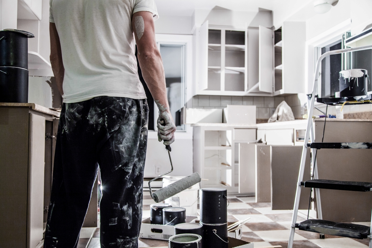 Man holding paint roller looking at finished kitchen paint job