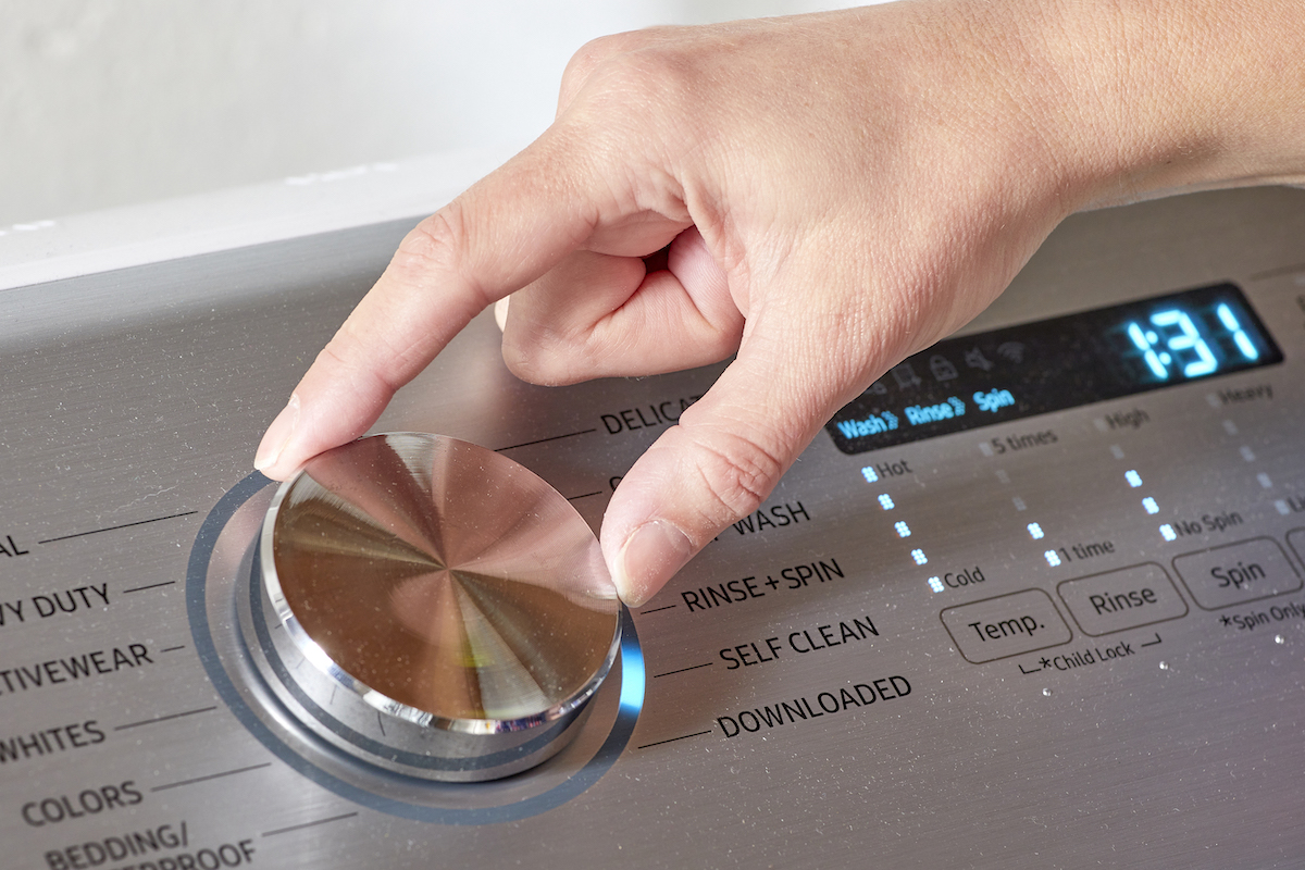 Woman turns the dial on her washing machine to "self clean."