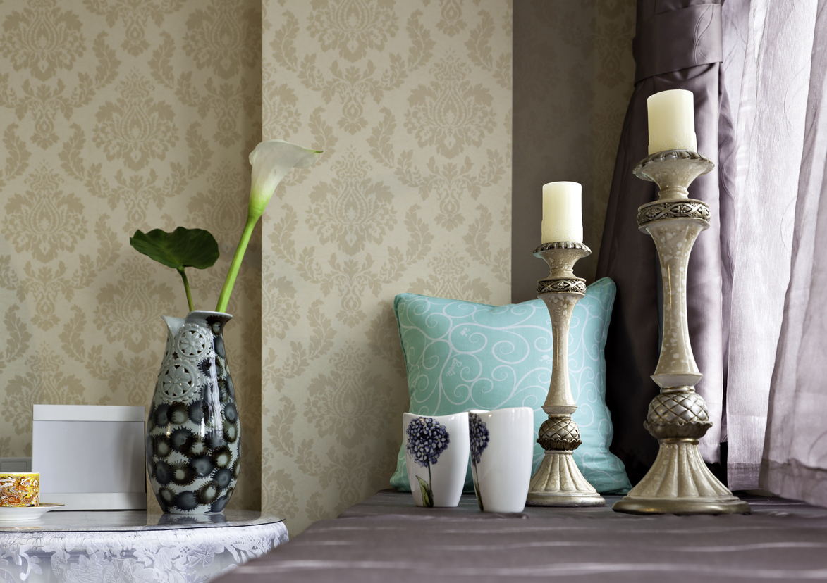 candles on windowsill with purple curtains and beige wallpaper.