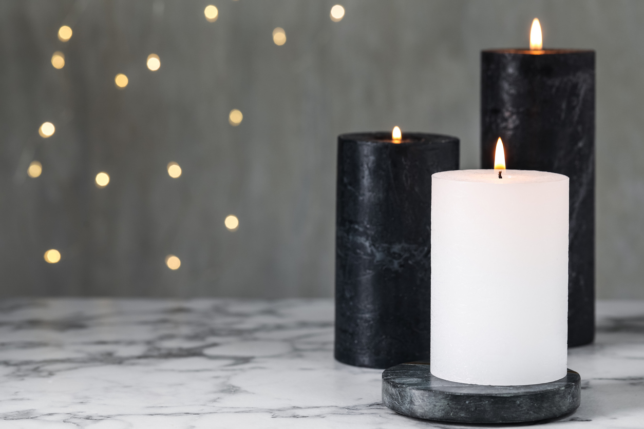 Burning candles on white vinyl table against blurred lights