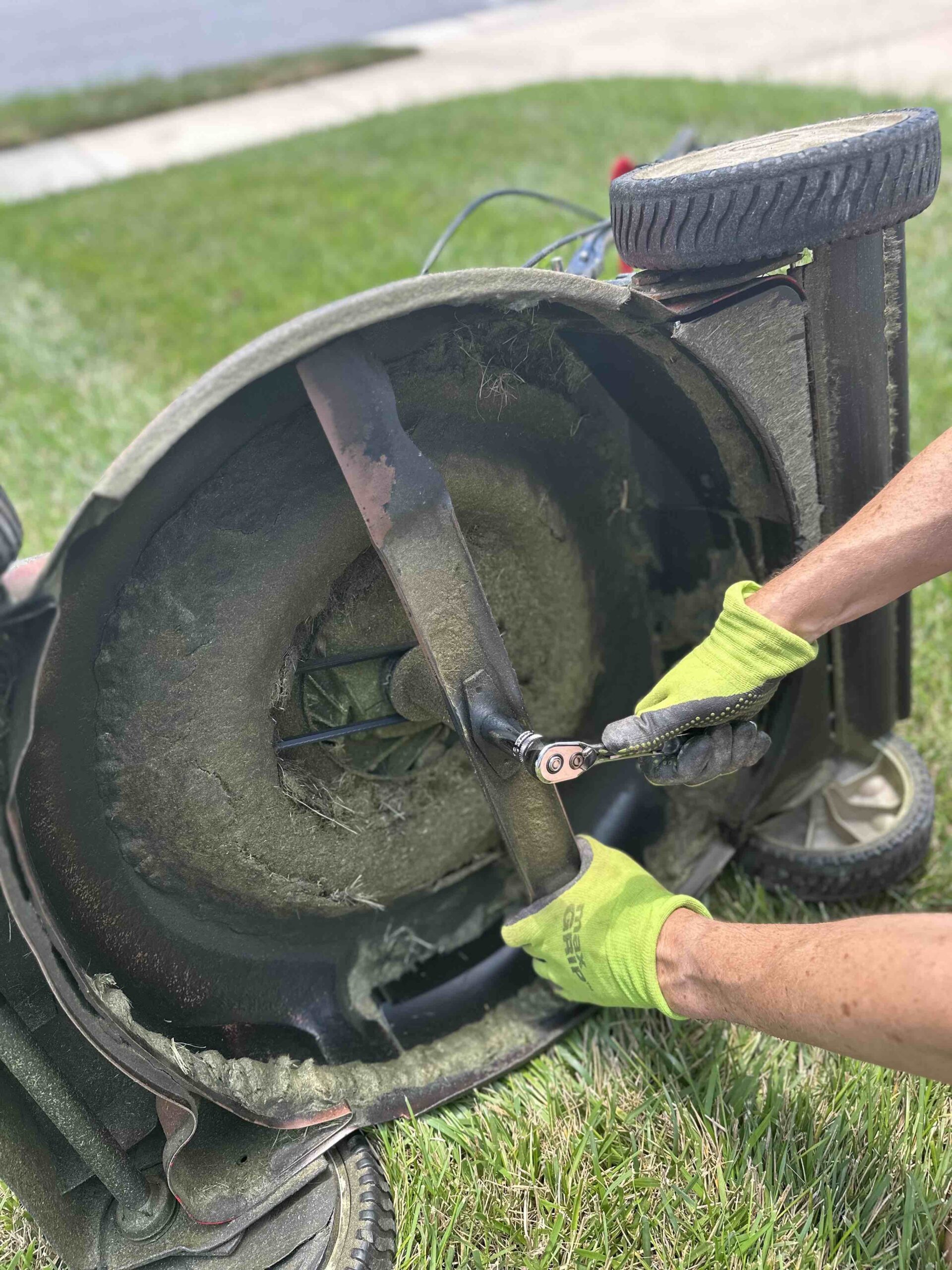 man loosening nut on lawn mower blade