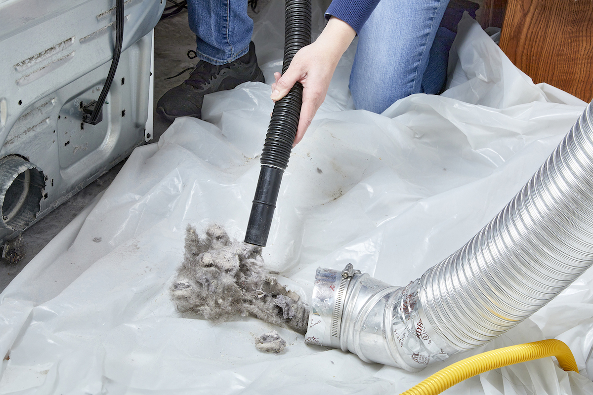 Woman vacuuming lint and debris from inside her dryer vent hose.