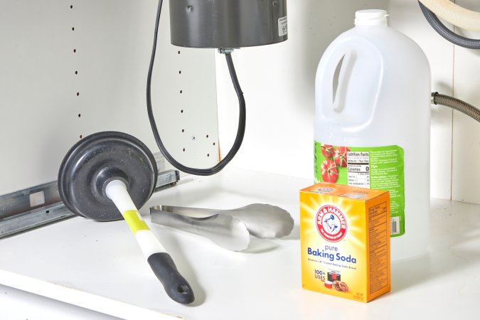 Materials for unclogging a garbage disposal under a sink, including plunger, vinegar, baking soda, etc.