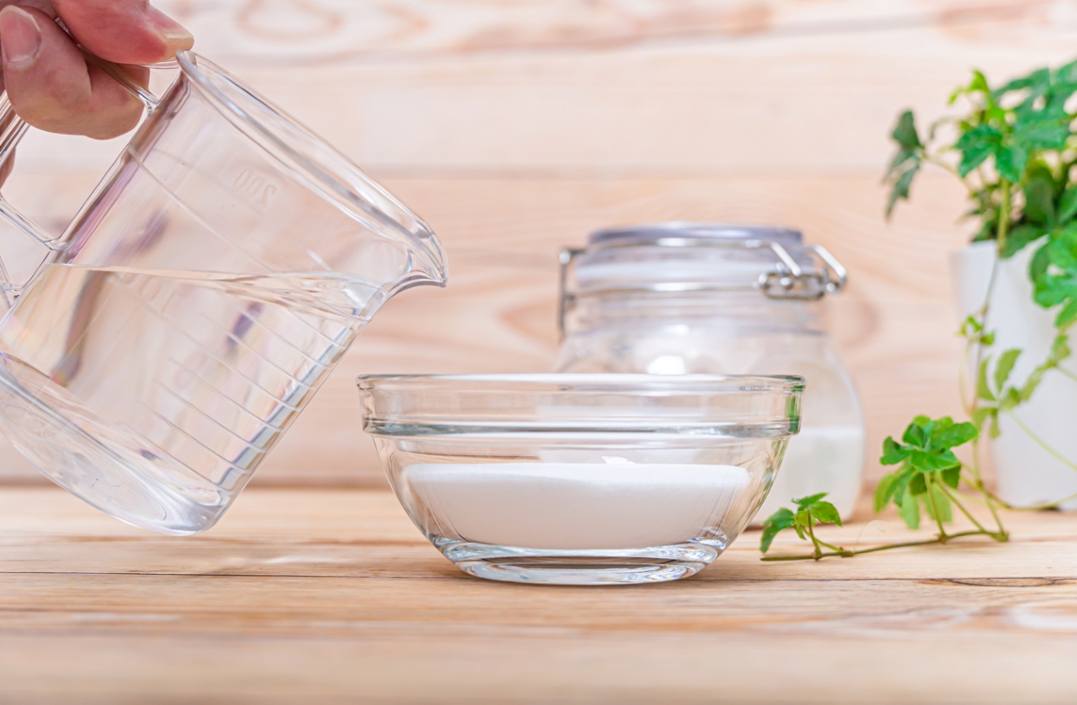 Pouring water from measuring cup into small bowl with baking soda.