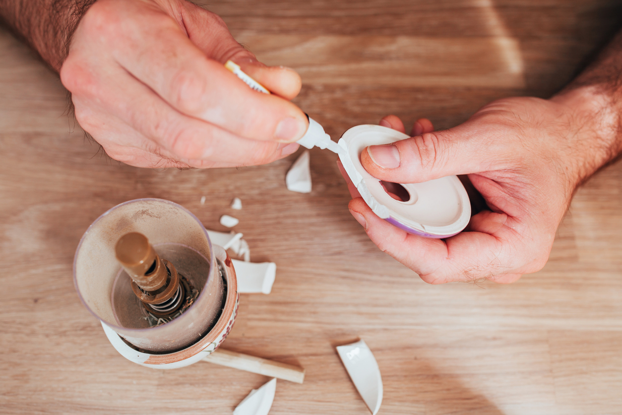 Male hands glue together fragments of ceramic dishes - superglue for repairing hard materials