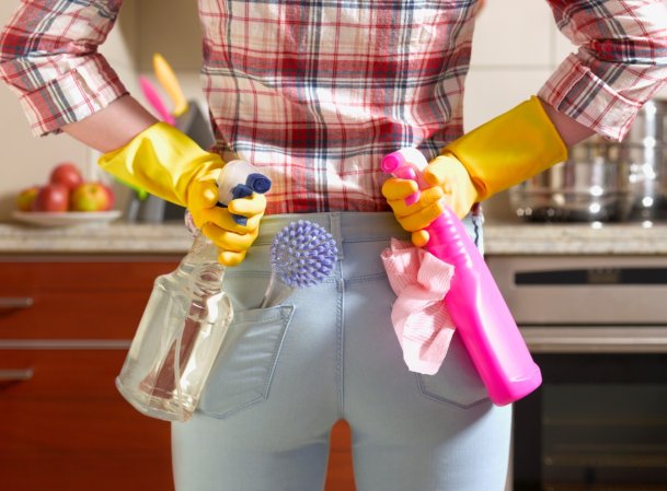 Someone wearing rubber gloves holding cleaning spray bottles and cloths