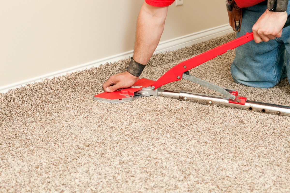 Person using power stretcher to install new carpet.